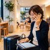 予約確認画面を見ながらホテルに到着時刻を電話で伝える宿泊者